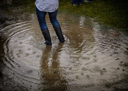 A person with gumboots standing in middle of a big puddle