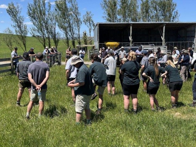 Farmers standing in a green field, attending a workshop
