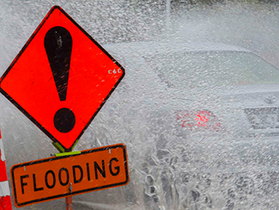 Car driving past flooding road sign