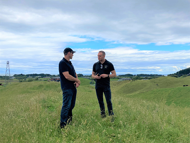 Two farmers standing in the middle of a farm and talking 