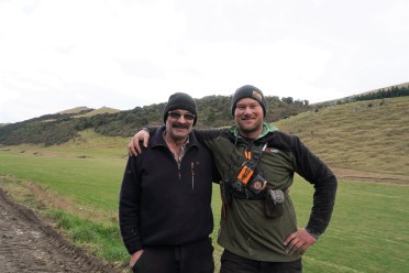 Two men standing with arms around each other's shoulders in a field