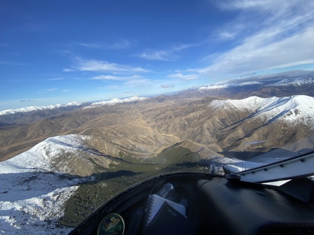 An aerial view of snow-capped mountains on a sunny day from the cockpit