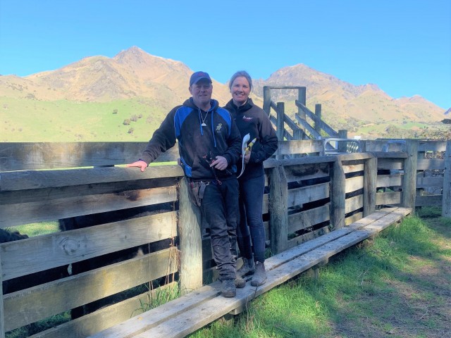 A couple standing at the farm gate, smiling for the camera