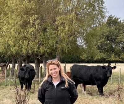 Image of OSPRI regional partner Tess standing in a field with 2 cows behind her